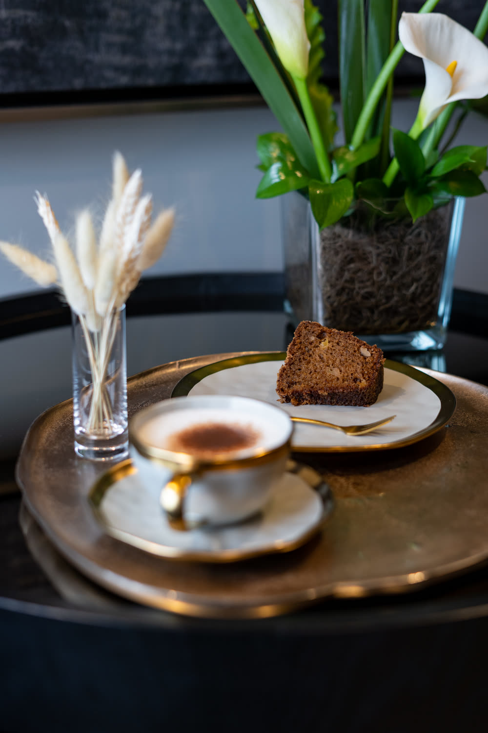 Café servido em xícara de porcelana com bolo, sobre bandeja dourada